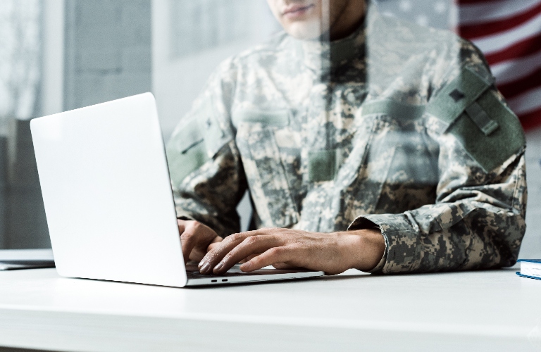 soldier in camouflage uniform using laptop